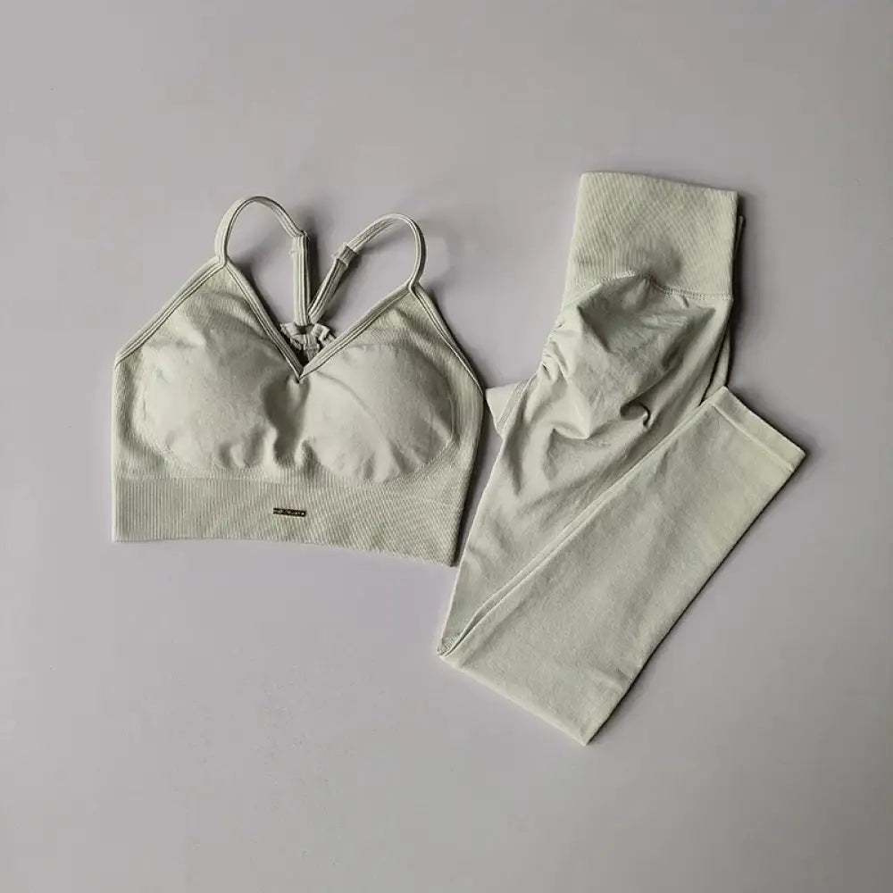 Un ensemble sportif deux pièces doux et vert clair, avec une brassière supportive à fines bretelles ajustables et un legging taille haute assorti en tissu tricot extensible.
