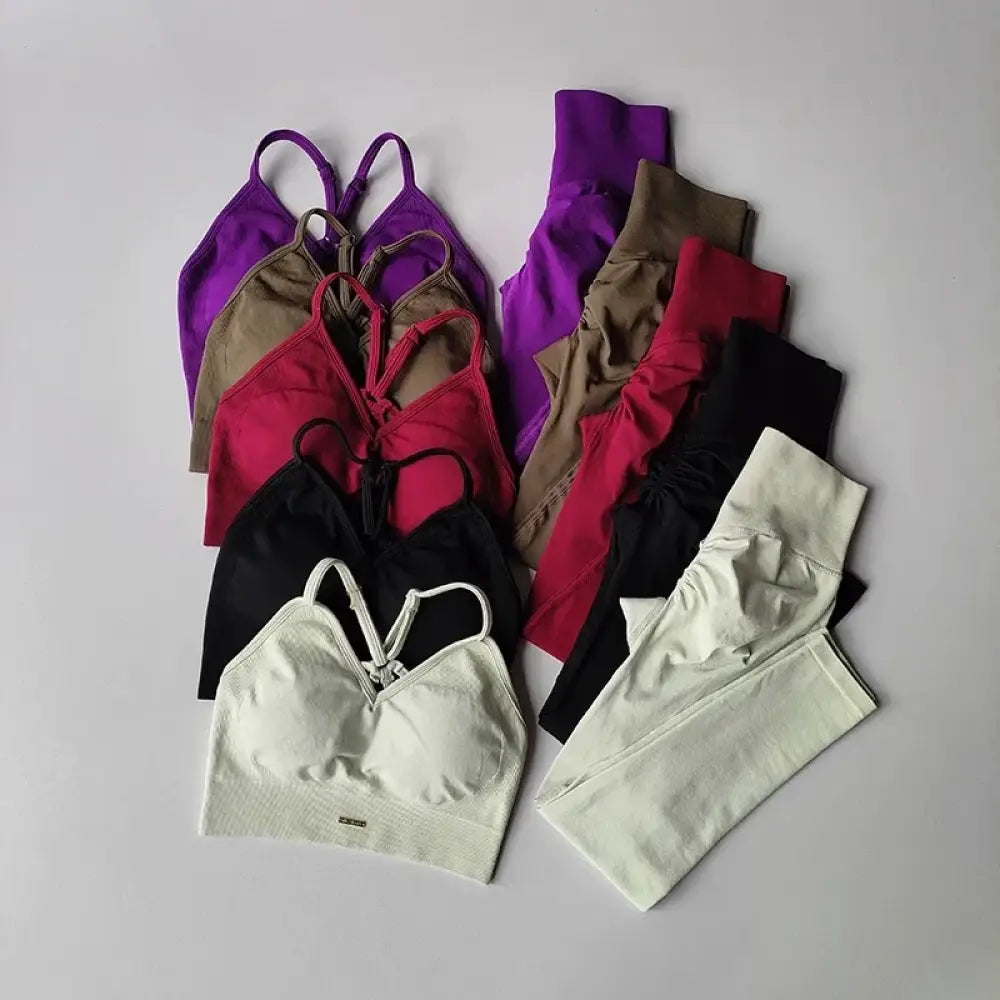 Une collection de soutiens-gorge de sport colorés, ajustés et de leggings assortis dans diverses nuances incluant le violet, le rouge, le noir, le beige et le blanc.