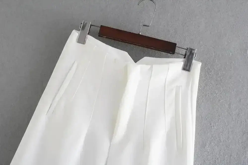 Pantalon tailleur victoire blanc à plis suspendu sur cintre en bois en matière tissée premium coupe pencil taille haute femme